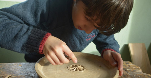Bambino che intaglia un piatto di legno