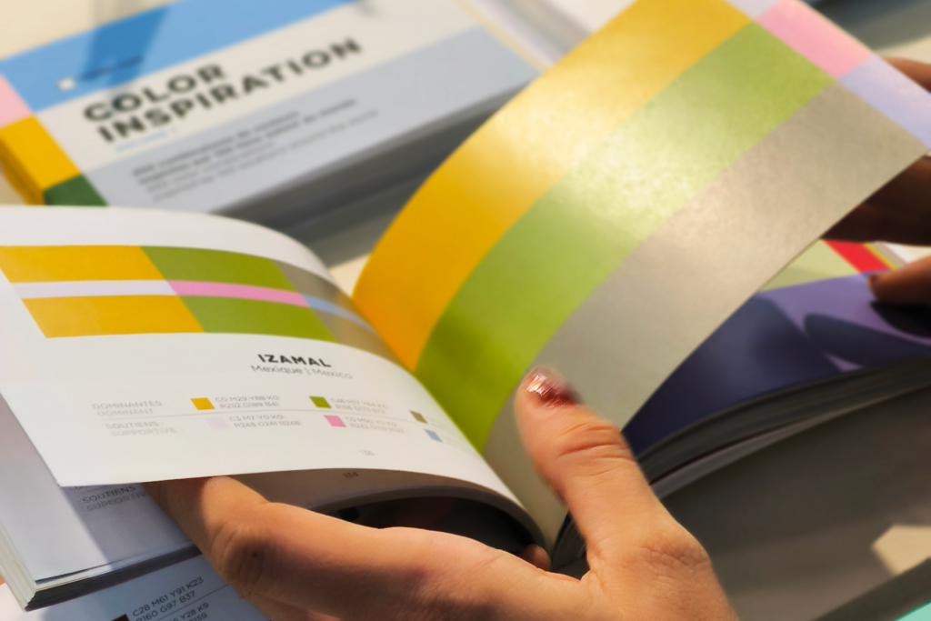 Mani che sfogliano un libro contenente palette cromatiche.